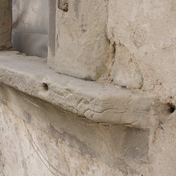 Detailansicht eines Fensterbankes mit markanten Schäden wie Schalenbildungen und Rissen